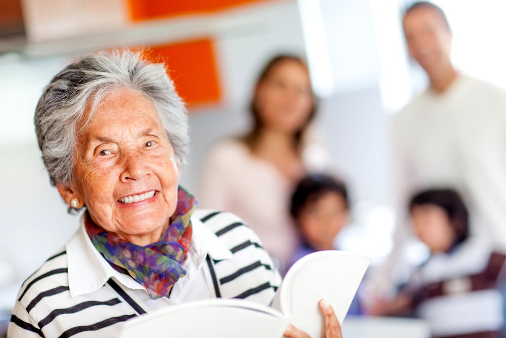 Happy grandmother holding a book of recipes and smiling