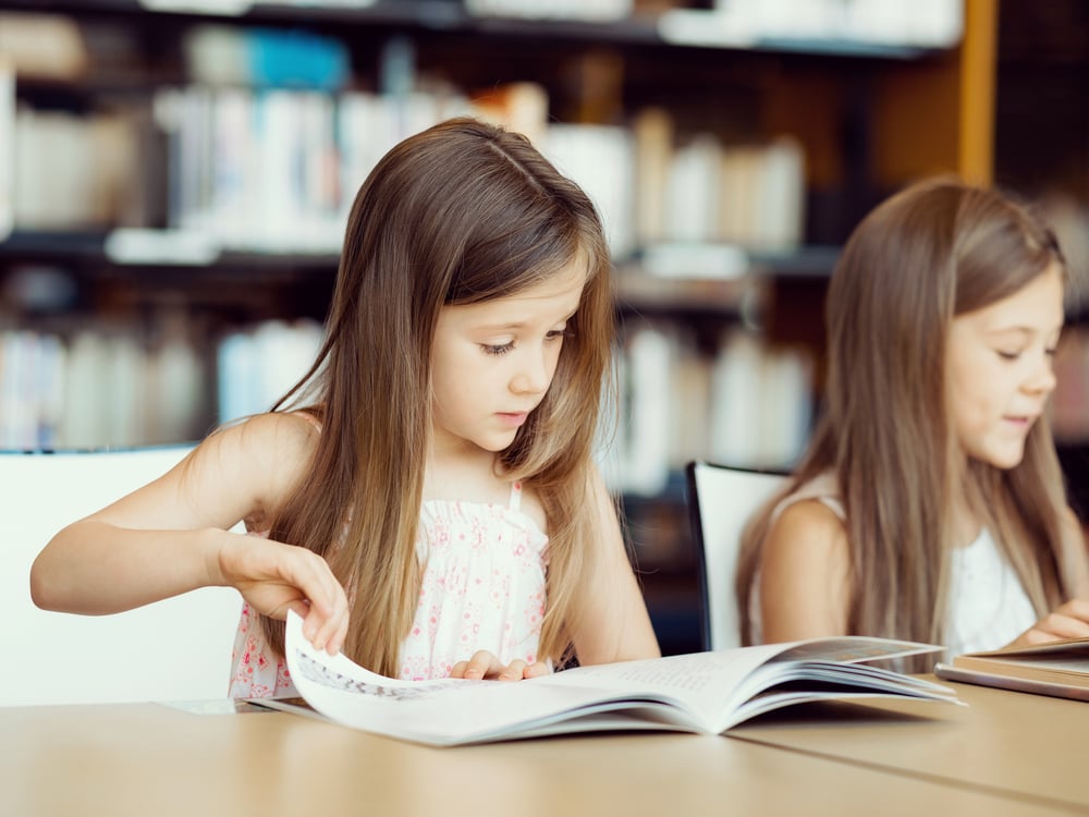 Little girls reading books in library