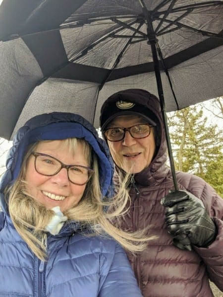 Annamarie under an umbrella bundled up in a snowy weather with a friend.