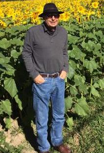 Tom standing happily in front a field of Sunflowers