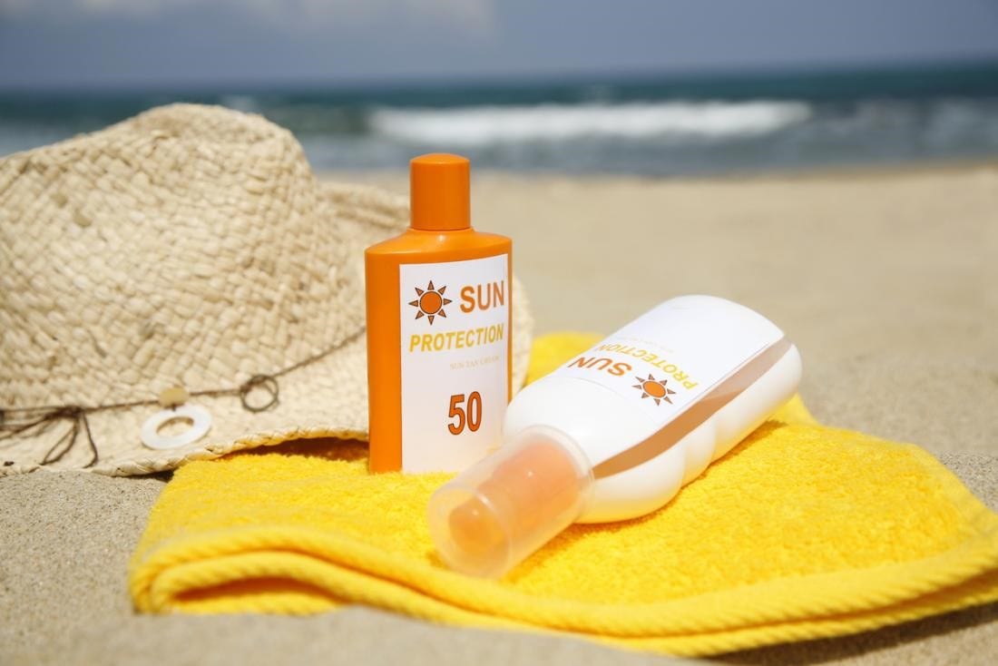 Sunblock lotions with a hat on a beach