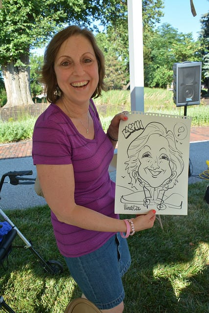 Lynn holding a character drawing of herself during a cancer support society event.
